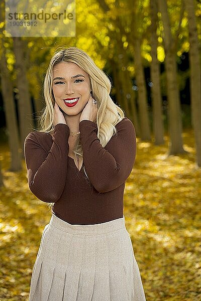 Ein wunderschönes blondes Model posiert im Freien und genießt das Herbstwetter