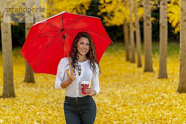 Ein schönes brünettes Modell genießt einen Herbsttag mit gelbem Herbstlaub