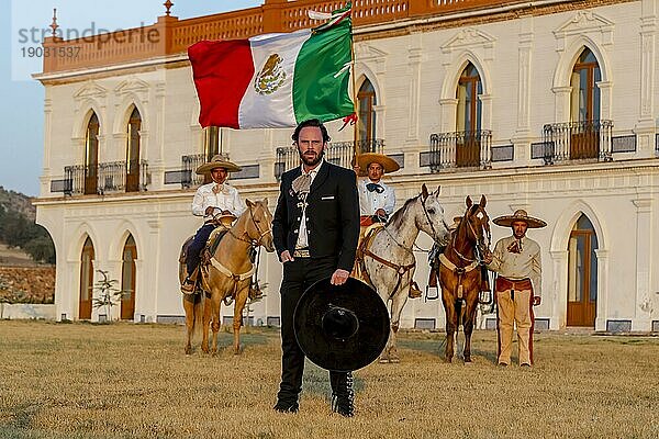 Ein stattlicher mexikanischer Charro posiert vor einer Hazienda in der mexikanischen Landschaft