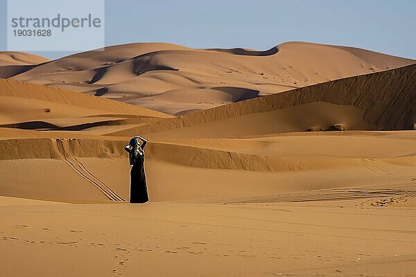 Ein schönes Model posiert vor den Sanddünen in der großen Saharawüste in Marokko