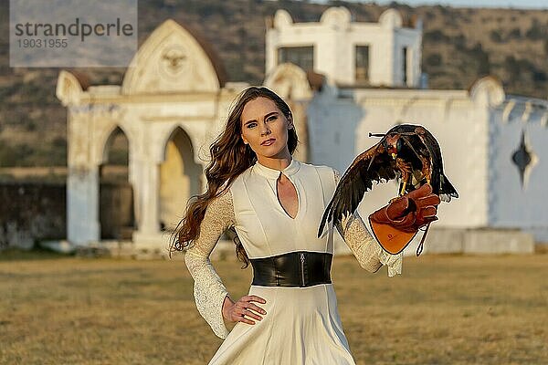 Eine wunderschöne Hispanic Brunette Modell posiert im Freien mit einem Falken im Freien auf einer Hazienda