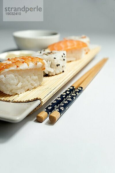 Shrimp Sushi mit Reis auf einem weißen Teller mit grauem Hintergrund unscharf