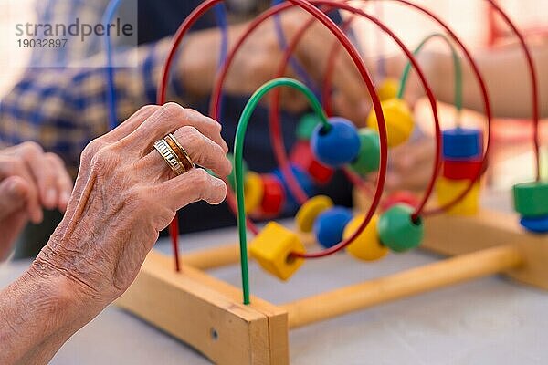 Die Hände zweier älterer Menschen im Garten eines Pflegeheims oder Seniorenheims  die mit Spielen zur Verbesserung der Beweglichkeit der Hände spielen