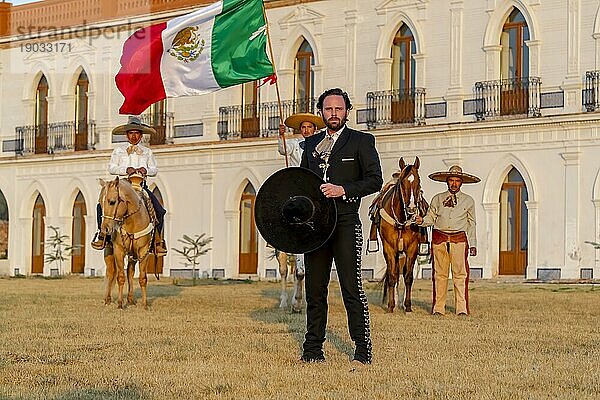 Ein stattlicher mexikanischer Charro posiert vor einer Hazienda in der mexikanischen Landschaft