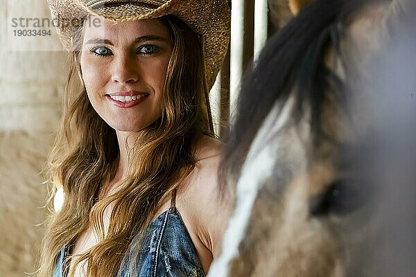 Ein wunderschönes Hispanic Brunette Modell posiert mit einem Pferd im Freien in einem mexikanischen Stall