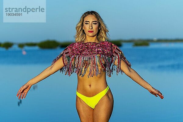 Ein schönes Model posiert mit der aufgehenden Sonne an einem exotischen karibischen Strand