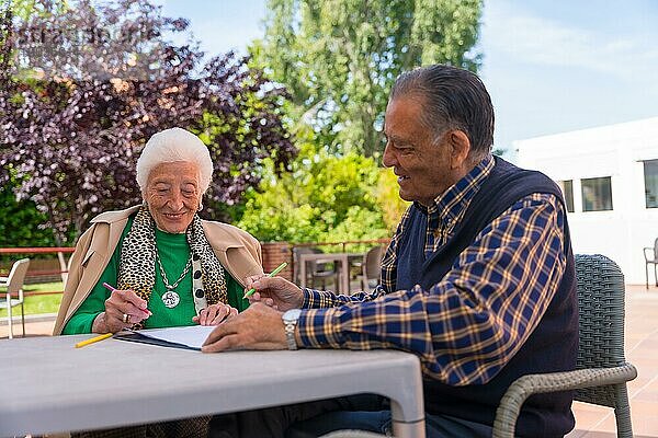 Zwei ältere Menschen malen im Garten eines Pflegeheims oder Seniorenheims  alter Mann und alte Frau