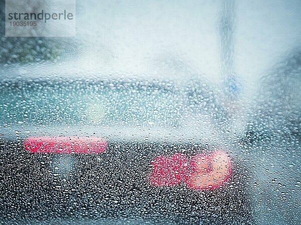 Rotes Gegenlicht eines Autos im Regen Fokus auf Regentropfen