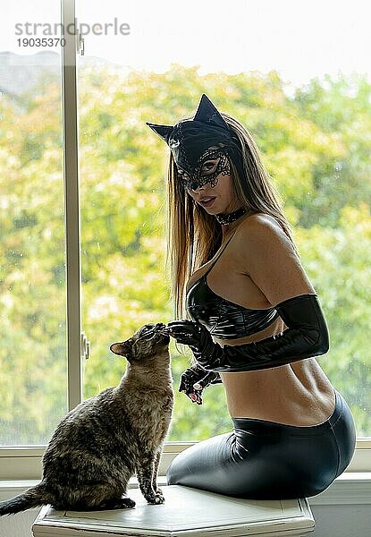 Ein wunderschönes brünettes Model posiert in einem Katzenkostüm mit ihrem Tier in einer häuslichen Umgebung