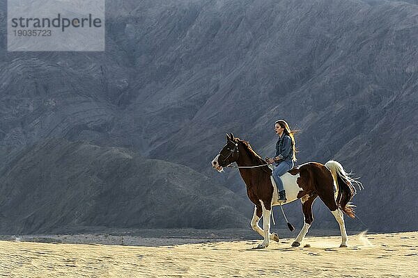 Eine junge brünette Frau verbringt Zeit mit ihrem Pferd in einer Wüstenumgebung