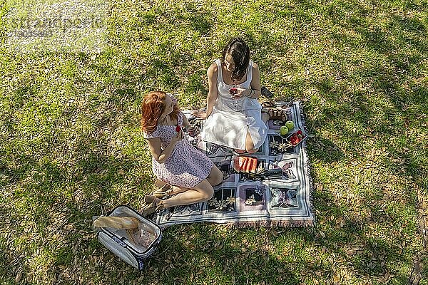 Zwei wunderschöne Modelle genießen die Gesellschaft des anderen an einem Herbsttag mit einem Picknick