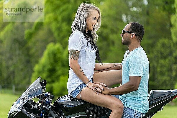 Ein gemischtrassiges Paar genießt einen Sommertag auf dem Motorrad