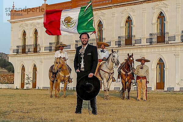 Ein stattlicher mexikanischer Charro posiert vor einer Hazienda in der mexikanischen Landschaft