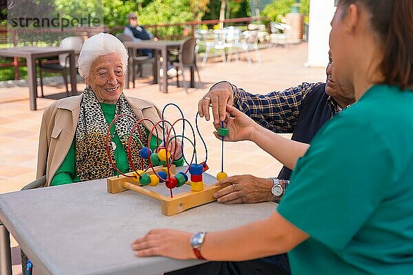 Zwei ältere Menschen im Garten eines Pflegeheims oder Seniorenheims  die mit Spielen zur Verbesserung der Mobilität spielen