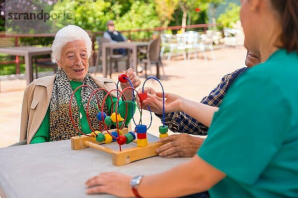 Zwei ältere Menschen im Garten eines Pflegeheims oder Seniorenheims  die mit Spielen zur Verbesserung der Mobilität spielen