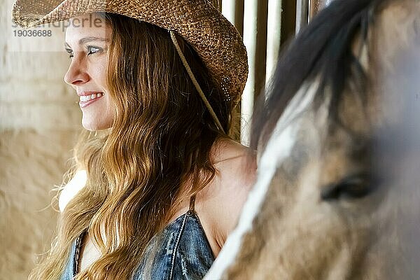 Ein wunderschönes Hispanic Brunette Modell posiert mit einem Pferd im Freien in einem mexikanischen Stall