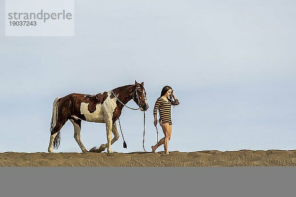 Eine junge brünette Frau verbringt Zeit mit ihrem Pferd in einer Wüstenumgebung