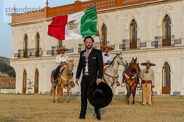 Ein stattlicher mexikanischer Charro posiert vor einer Hazienda in der mexikanischen Landschaft