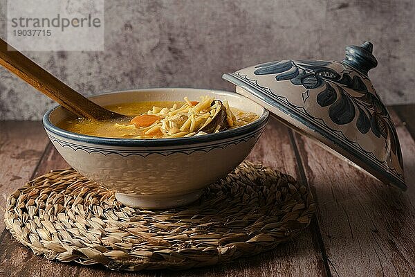 Suppenterrine mit Hühnersuppe mit Nudeln auf einem Holztisch