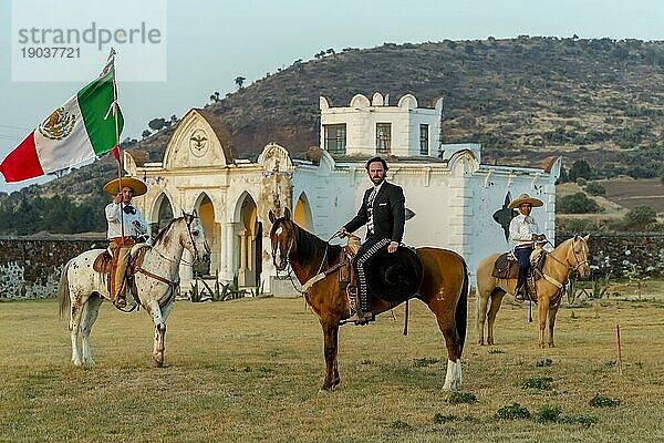 Ein stattlicher mexikanischer Charro posiert vor einer Hazienda in der mexikanischen Landschaft