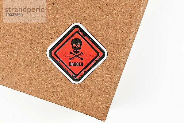 Rotes Warnschild mit Totenkopf und dem Wort Gefahr auf dem Paket