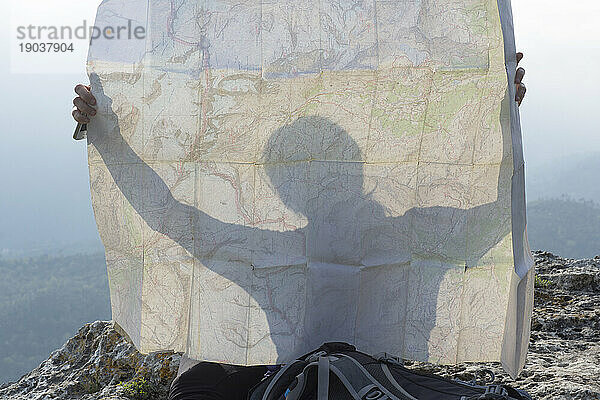 Detail einer Frau  die in der Karte auf einer Klippe über den Bergen silhouettiert ist