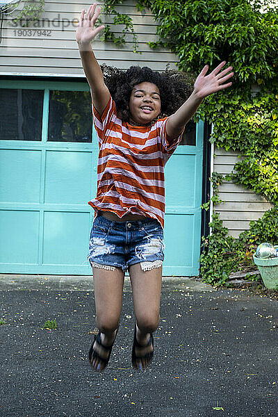Tween girl in backyard jumping