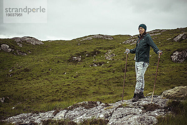 Stolze  starke Wanderin steht mit Stöcken auf einem abgelegenen Berg