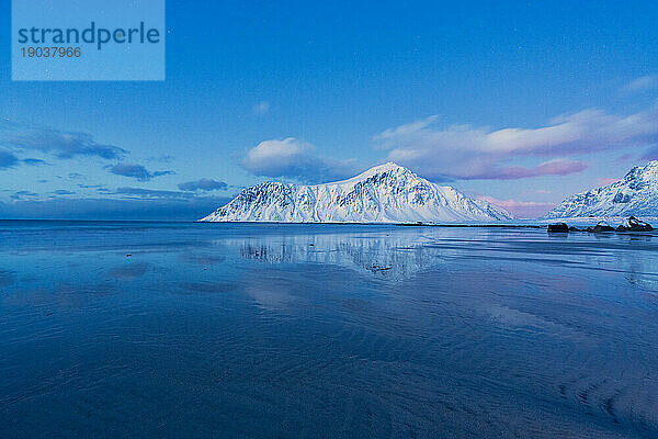 Schneebedeckte Gipfel spiegeln sich im kalten Meer  Strand von Skagsanden  Norwegen