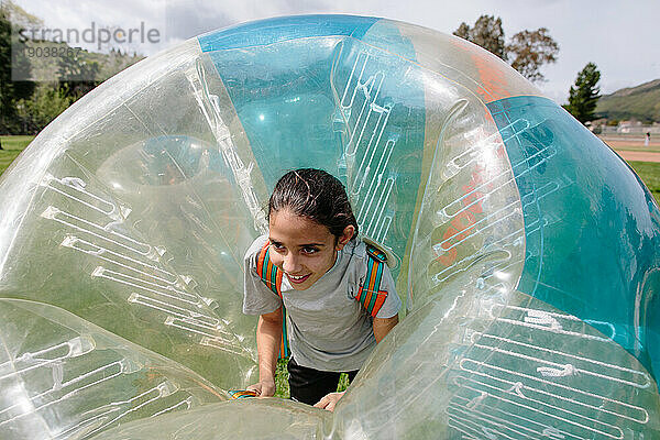 Tween-Mädchen lächelt  während es in einem Bubble-Soccer-Bubble-Anzug steckt