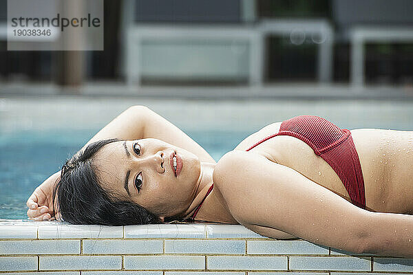 schöne thailändische Frau  die sich am Pool entspannt