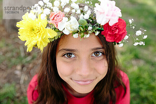 Tween-Mädchen lächelt in die Kamera  während sie einen Blumenkranz trägt