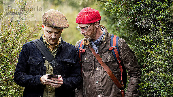 Zwei Männer auf einem Wanderweg schauen auf ihr Smartphone