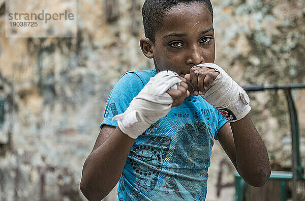 Ein ernsthafter junger kubanischer Junge nimmt in Boxhandschuhen eine Sparringshaltung ein. Projekt Cuba Boxeo  Alt-Havanna  La Havanna  Kuba