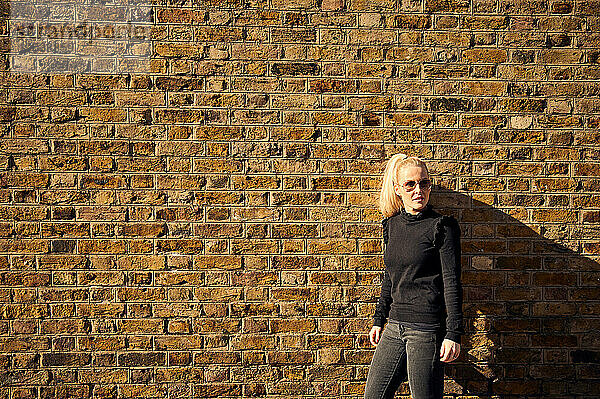 Attraktive Blondine posiert vor einer Mauer