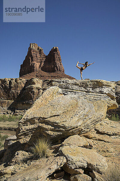Eine Frau macht eine Yoga-Pose in einer Wüstenlandschaft.