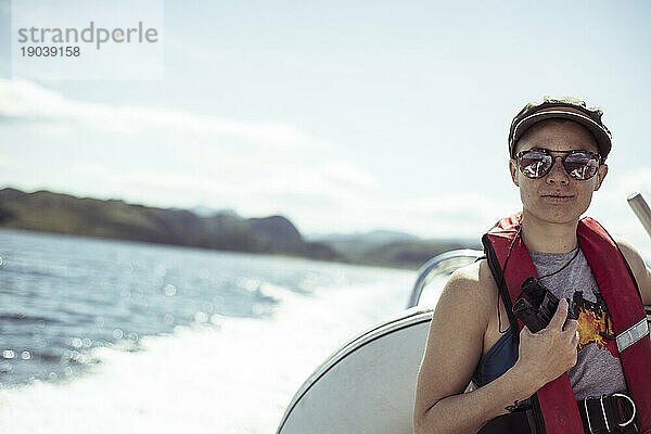 Mädchen auf Schnellboot lächelt mit Sonnenbrille und Schwimmweste