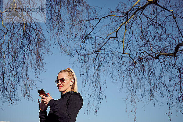 Attraktive Frau benutzt Smartphone im Park