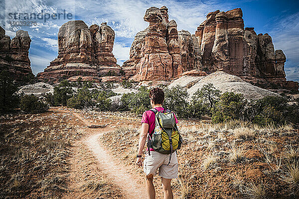 Eine Wanderin  die zwischen den ungewöhnlichen Sandsteinformationen im Canyonlands-Nationalpark spaziert.