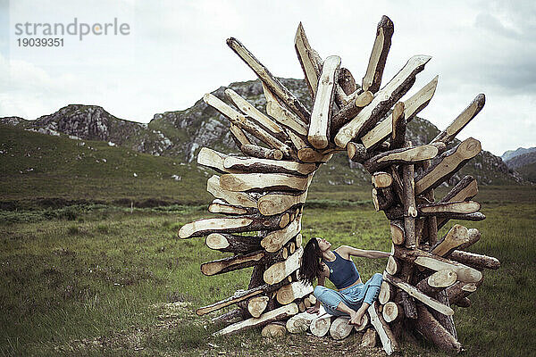 Mädchen sitzt in Holzskulptur in abgelegenen Bergen