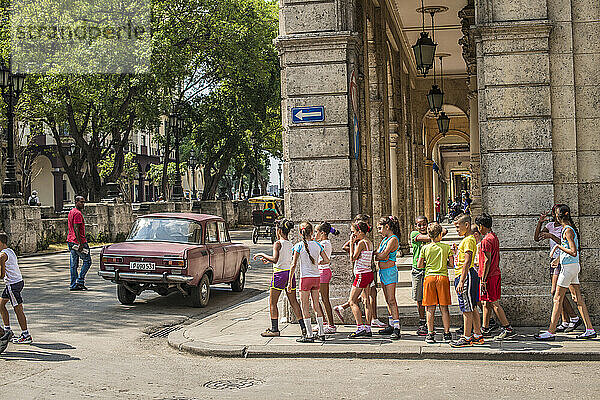 Eine Gruppe von Schulkindern geht an einer Straßenecke unter den Bögen eines Kolonialgebäudes in Havanna Centro  La Habana  Kuba