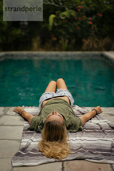 Eine junge Frau liegt am Pool.