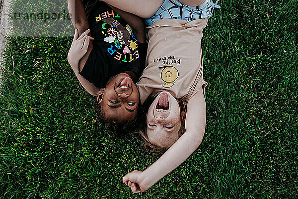 Zwei Mädchen machen im Gras alberne Gesichter