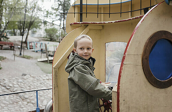 kleiner Junge lächelt  während er ein Spielzeugboot fährt