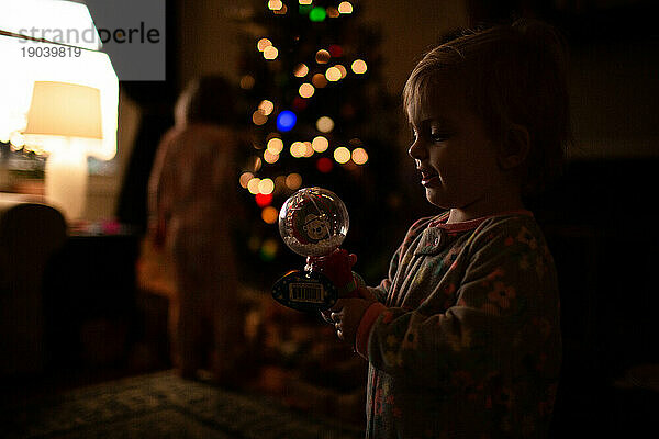 Kleinkind/Baby hält Spielzeug und lächelt am Weihnachtsmorgen