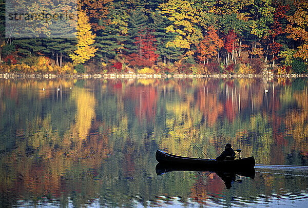 Mann fischt gemächlich vom Kanu aus während der Spitzenbelaubung am Walden Pond  Concord  Massachusetts.