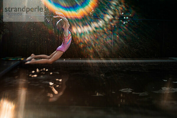 Junges Mädchen springt an einem sonnigen Tag auf den Pool