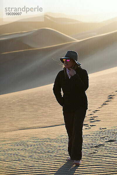 Nachdenkliche Frau mit heller  runder  reflektierender Sonnenbrille in der Wüste