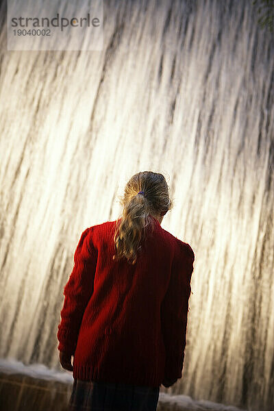 Silhouette einer Person vor einem Wasserfallbrunnen.