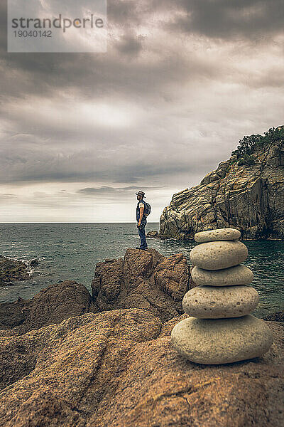Abenteuerlustiger Mann mit Fotokamera und Fernglas erkundet einen Felsen